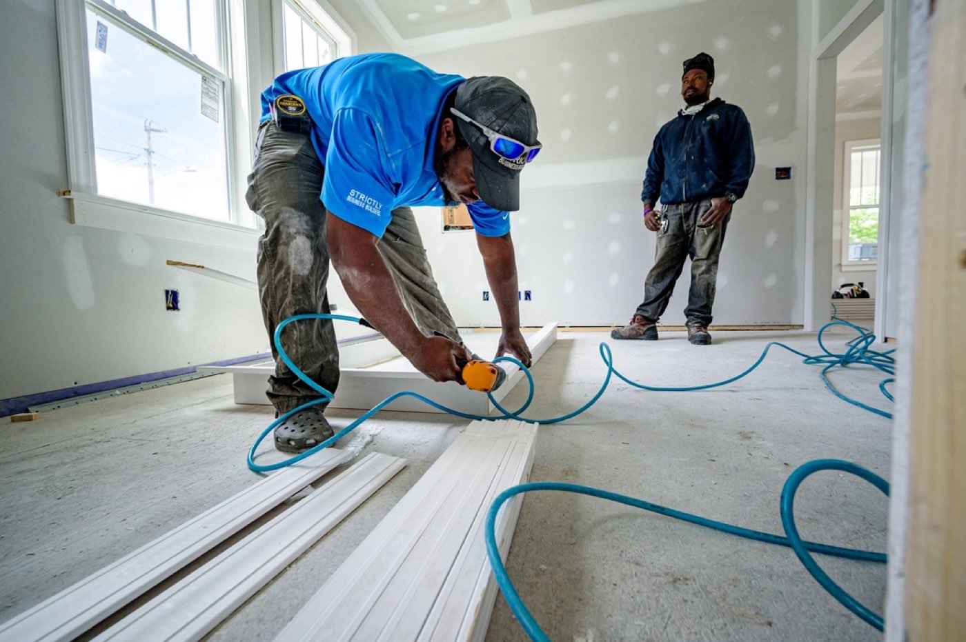 Two tradespeople installing flooring in a house under renovation